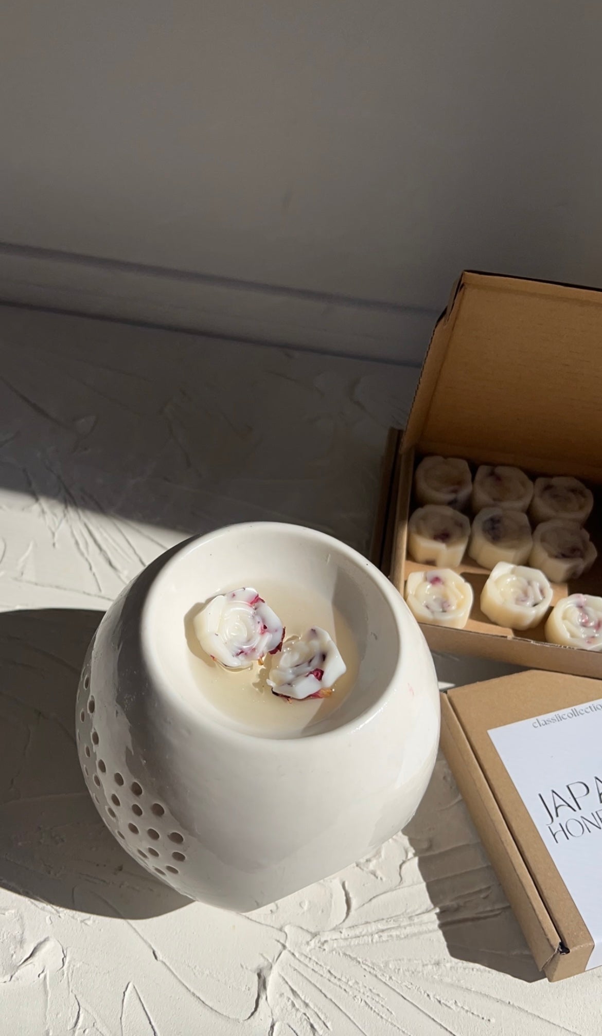 soy wax rose melts melting on a wax burner with a packet of soy wax melt boxes on the side 